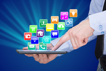 Image showing Businessman holding a tablet pc with mobile applications icons on virtual screen . Internet and business concept.