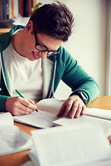 Image showing happy student boy writing to notebook in library