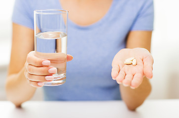 Image showing close up of woman hands with pills and water