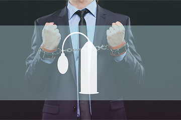 Image showing man in a business suit with chained hands. handcuffs for sex games. concept of erotic entertainment.