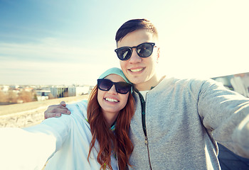 Image showing happy teenage couple taking selfie on city street