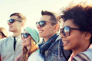 Image showing happy teenage friends in shades hugging outdoors