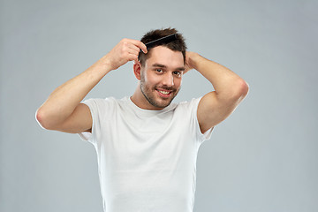Image showing happy man brushing hair with comb over gray