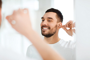 Image showing man cleaning ear with cotton swab at bathroom