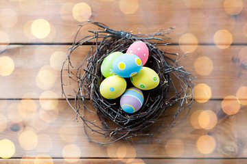 Image showing close up of colored easter eggs in nest on wood