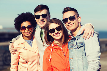 Image showing happy teenage friends in shades hugging outdoors