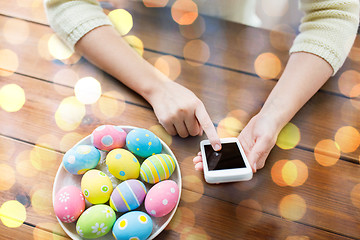 Image showing close up of hands with easter eggs and smartphone