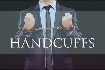 Image showing man in a business suit with chained hands. handcuffs for sex games. concept of erotic entertainment.