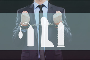 Image showing man in a business suit with chained hands. handcuffs for sex games. concept of erotic entertainment.