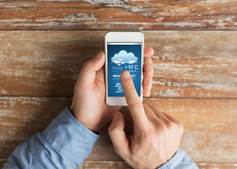 Image showing close up of male hands with smartphone on table