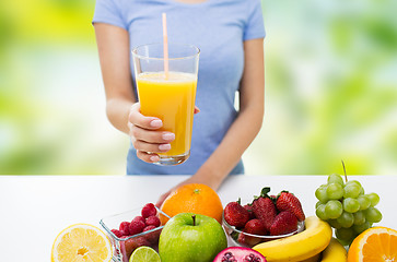 Image showing close up of woman holding orange juice with fruits