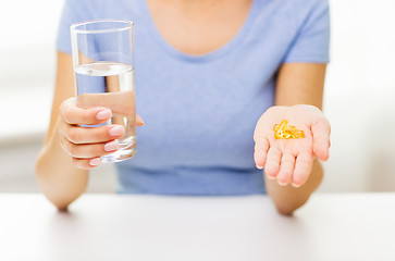 Image showing close up of woman hands with capsules and water
