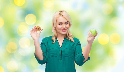 Image showing smiling woman choosing between apple and cookie