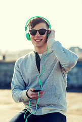 Image showing happy young man in headphones with smartphone