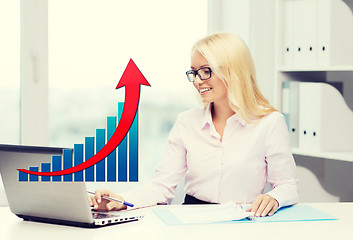 Image showing smiling businesswoman with laptop and papers