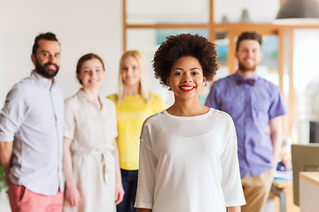 Image showing happy young woman over creative team in office