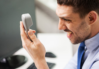 Image showing angry businessman calling on phone in office