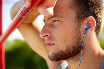 Image showing young man with earphones and horizontal bar