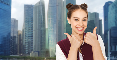 Image showing happy teenage girl showing thumbs up over city