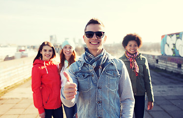 Image showing happy teenage friends showing thumbs up on street