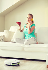 Image showing happy woman with smartphone drinking tea at home