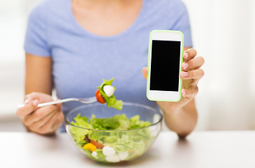 Image showing close up of woman with smartphone eating salad