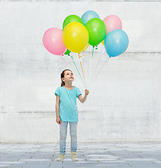 Image showing girl looking up with bunch of helium balloons