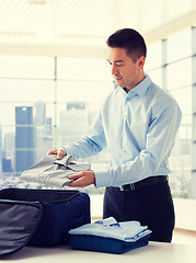 Image showing businessman packing clothes into travel bag