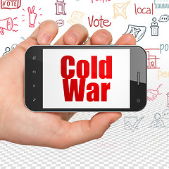 Image showing Political concept: Hand Holding Smartphone with Cold War on display