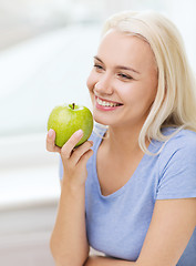 Image showing happy woman eating green apple at home