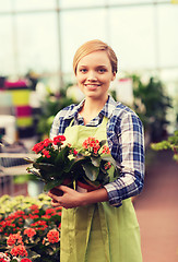 Image showing happy woman holding flowers in greenhouse
