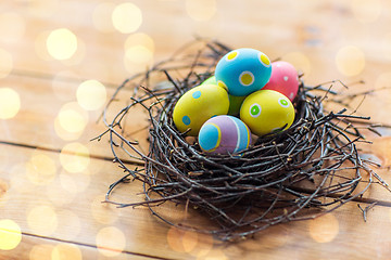 Image showing close up of colored easter eggs in nest on wood