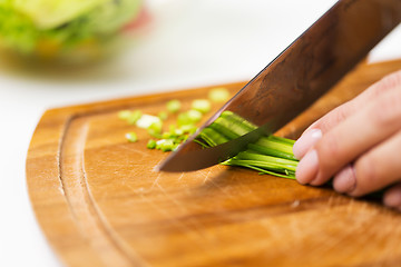 Image showing close up of woman chopping green onion with knife