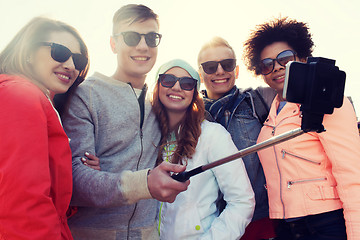 Image showing friends taking selfie with smartphone on stick