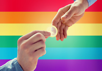 Image showing close up of male gay couple hands giving condom