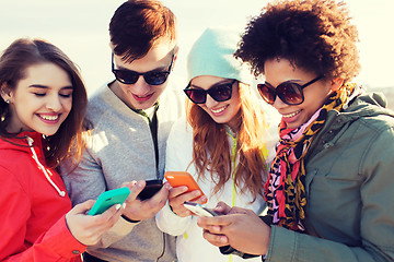 Image showing smiling friends with smartphones