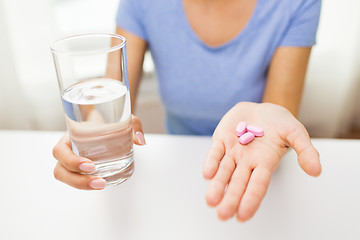 Image showing close up of woman hands with pills and water