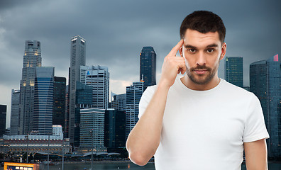 Image showing man with finger at temple over singapore city