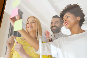 Image showing happy creative team writing on stickers at office