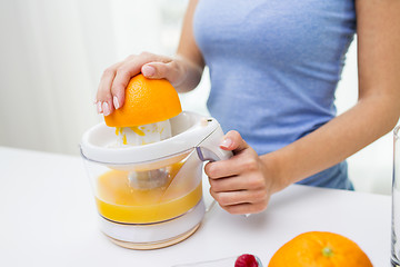 Image showing close up of woman squeezing orange juice at home