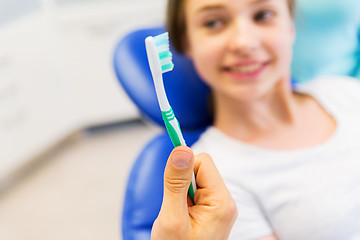 Image showing close up of dentist hand with toothbrush and girl