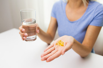 Image showing close up of woman hands with capsules and water