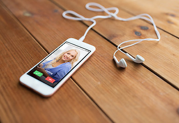 Image showing close up of smartphone and earphones on wood