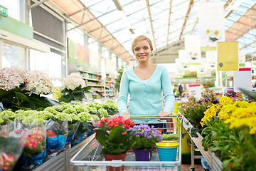 Image showing happy woman with shopping cart and flowers in shop