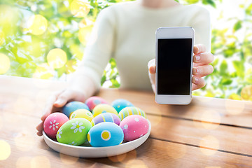Image showing close up of woman with easter eggs and smartphone