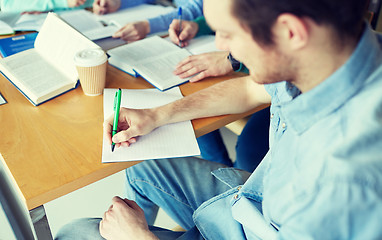 Image showing happy students writing to notebooks in library