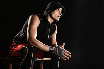 Image showing The muscular man sitting and resting on black