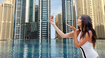 Image showing woman taking selfie with smartphone over city pool