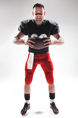 Image showing American football player posing with ball on white background