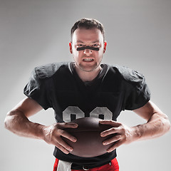 Image showing American football player posing with ball on white background